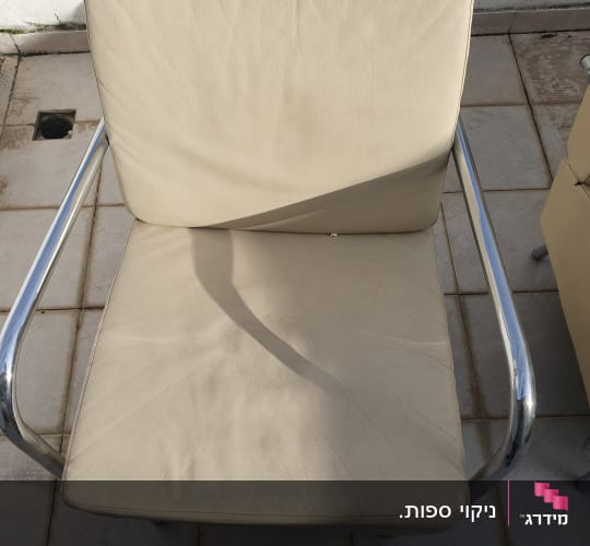 כורסת עור בהירה נקייה ומתוחה עם ידיות מתכת
